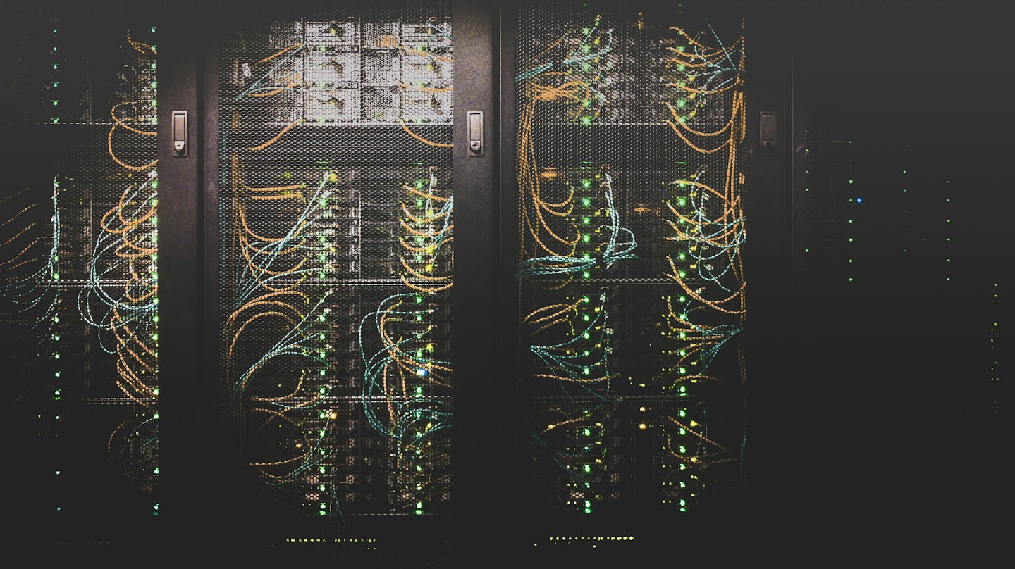 Racks de servidores con luces verdes parpadeantes y cables de colores.