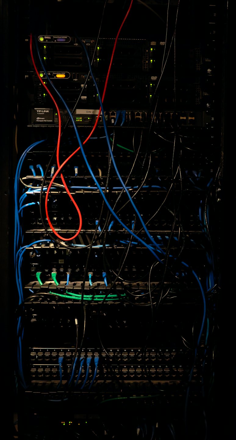 Rack de servidores con cables de red azules y rojos enredados.